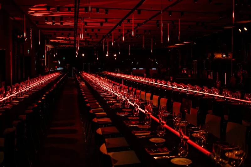 Longue tablée dans un lieu industriel mis en lumière rouge