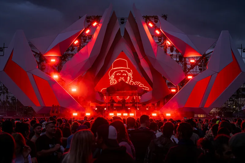 Scène de festival rouge illuminée par des faisceaux lumineux